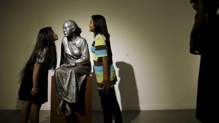 Students pose near a sculpture by Indonesian artist Purjito at National Gallery in Jakarta, Indonesia.