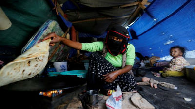 A woman makes bread inside her tent at a camp for internally displaced people near Sanaa, Yemen. Picture:REUTERS