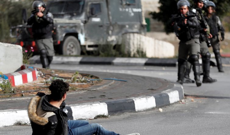 A Palestinian man with a knife in his hand falls after being shot by Israeli border policemen near the Jewish settlement of Beit El, near the West Bank city of Ramallah, December 15, 2017. REUTERS/Goran Tomasevic