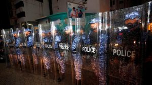 Maldivian police stand guard on a main street during a protest.