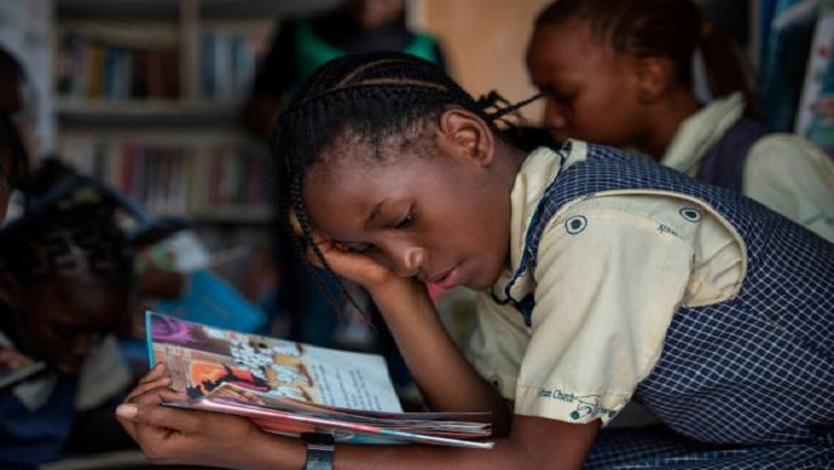 A girl reads through a book in the I-Read mobile library.