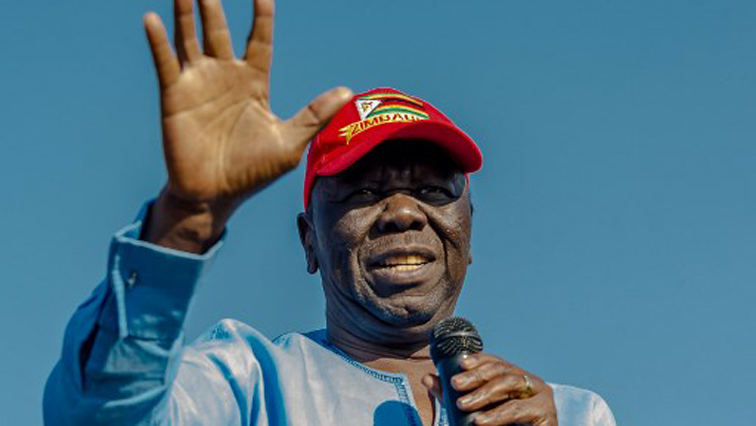 Picture of Morgan Tsvangirai wearing a red cap and blue shirt and holding a microphone.