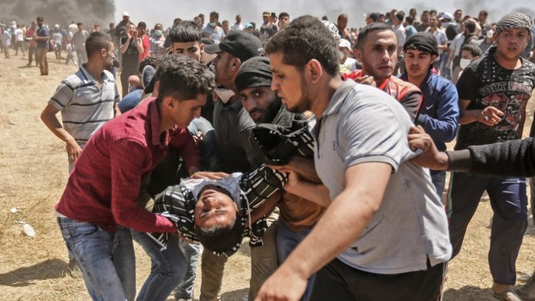 Palestinians carry an injured man during clashes with Israeli forces near the border between the Gaza strip and Israel east of Gaza City on May 14, 2018, as Palestinians protest over the inauguration of the US embassy following its controversial move to Jerusalem.
Dozens of Palestinians were killed by Israeli fire on May 14 as tens of thousands protested and clashes erupted along the Gaza border against the US transfer of its embassy to Jerusalem, after months of global outcry, Palestinian anger and exuberant praise from Israelis over President Donald Trump's decision tossing aside decades of precedent. / AFP PHOTO / MAHMUD HAMS