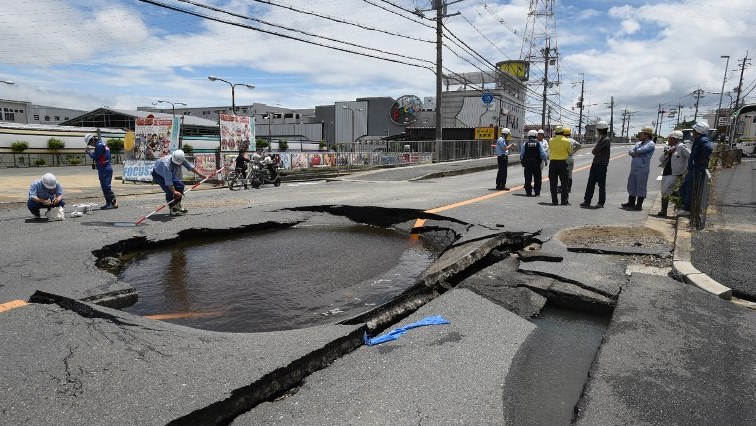 Workers stand by a partially collapsed road following an earthquake in Takatsuki, north of Osaka prefecture on June 18, 2018.