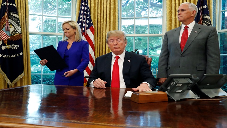 DHS Secretary Kirstjen Nielsen (L) looks at the executive order on immigration policy after U.S. President Donald Trump signed it and handed it to her as Vice President Mike Pence stands at his other side in the Oval Office at the White House.