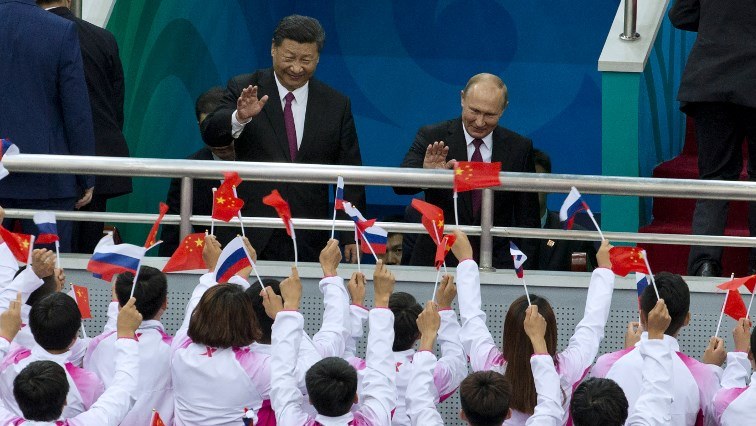 Russian President Vladimir Putin (R) and Chinese President Xi Jinping (L) wave at  spectators.