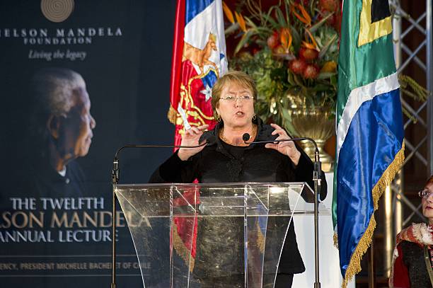 Michelle Bachelet, President of Chile, delivers an address about gender as part of the annual Nelson Mandela Lecture Series, in front of a picture of Mandela, and Chilean(L) and South African flags, at the University of Cape Town, on August 10, 2014, in Cape Town.