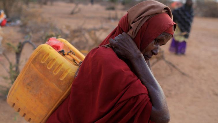 An internally displaced woman from drought hit area carries a jerrycan of water as she walks towards her shelter at a makeshift settlement area in Dollow, Somalia.