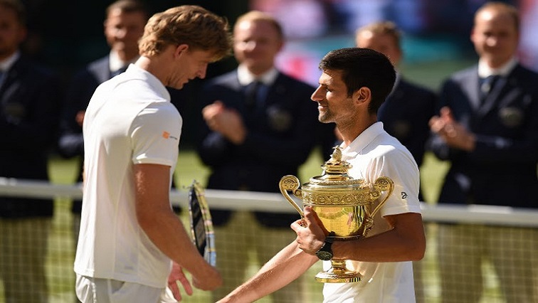 Serbia's Novak Djokovic smiles as he carries the winners trophy after beating South Africa's Kevin Anderson.
