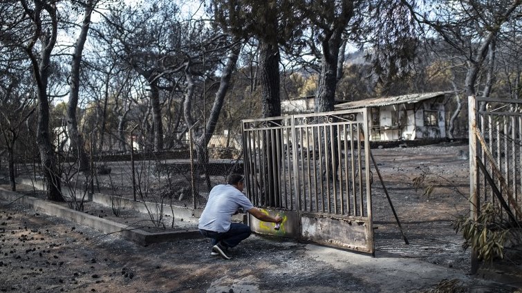 A expert marks with paint a burnt house following a wildfire at the village of Neos Voutzas, near Athens on July 26, 2018.