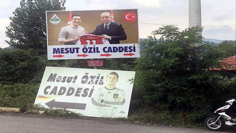 A billboard, serving as a street sign, with a picture of Arsenal's soccer player Mesut Ozil in the German national team kit is replaced by a picture of him with Turkish President Tayyip Erdogan in the Black Sea town of Devrek in Zonguldak, Turkey July 24, 2018.