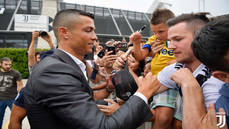 Cristiano Ronaldo signs autographs for Juve fans.