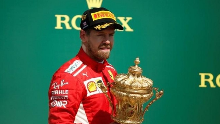 Ferrari's Sebastian Vettel celebrates winning the race on the podium with the trophy.
