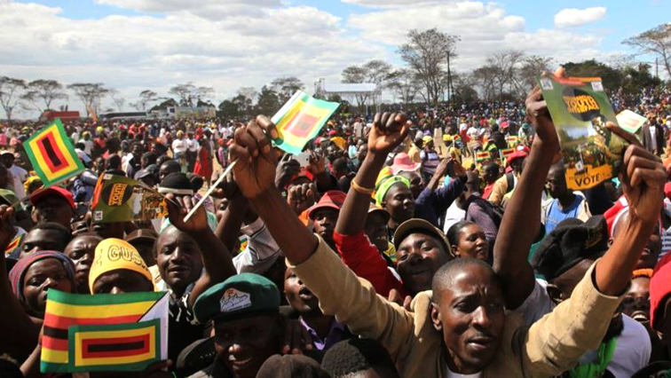 Picture of people carrying small Zimbabwean flags.