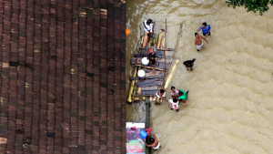 People wait for aid next to a makeshift raft at a flooded area in Kerala,