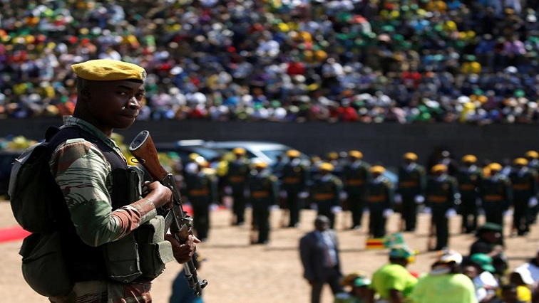 An soldier standing in the foreground with crowds behind him