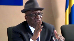 Bheki Cele talking with hands close to his mouth.