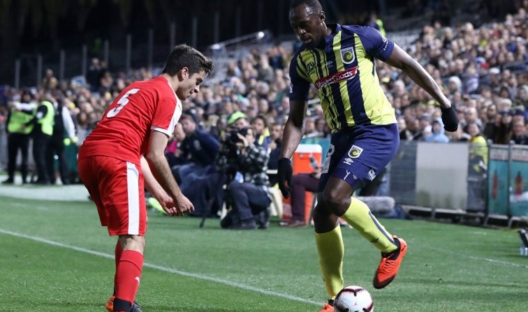 Olympic sprinter Usain Bolt (R), playing for A-League football club Central Coast Mariners, fights for the ball with a player from a Central Coast amateur selection team