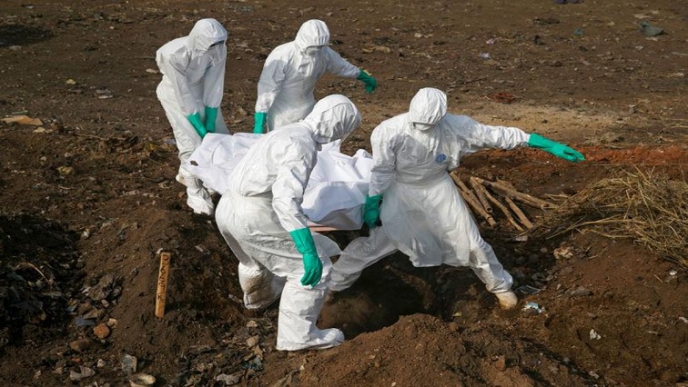 Health workers carry the body of a suspected Ebola victim for burial at a cemetery in Freetown, Sierra Leone, December 21, 2014.