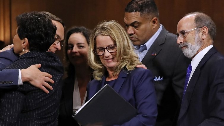 Christine Blasey Ford (C) is surrounded by her attorney Michael Bromwich (R), supporters and security agents