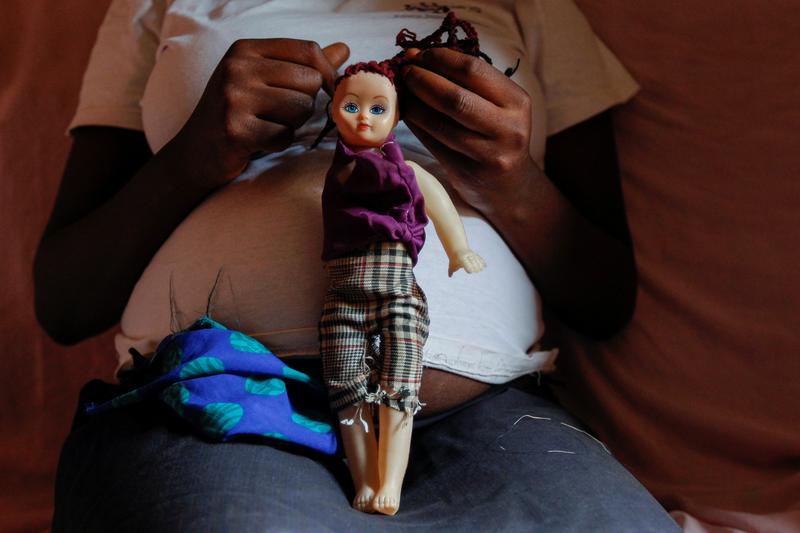A pregnant teenager seen playing with a doll