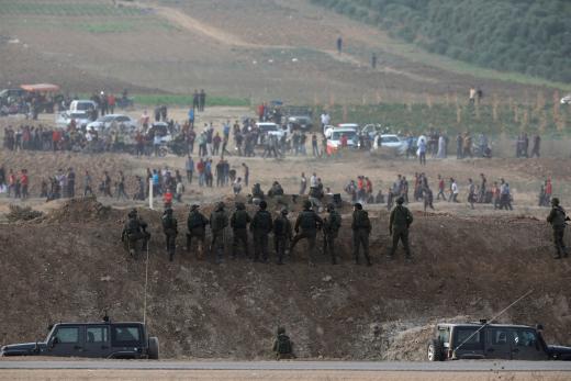 Israeli soldiers are seen next to the border fence on the Israeli side of the Israel-Gaza border as Palestinians protest on the Gaza.