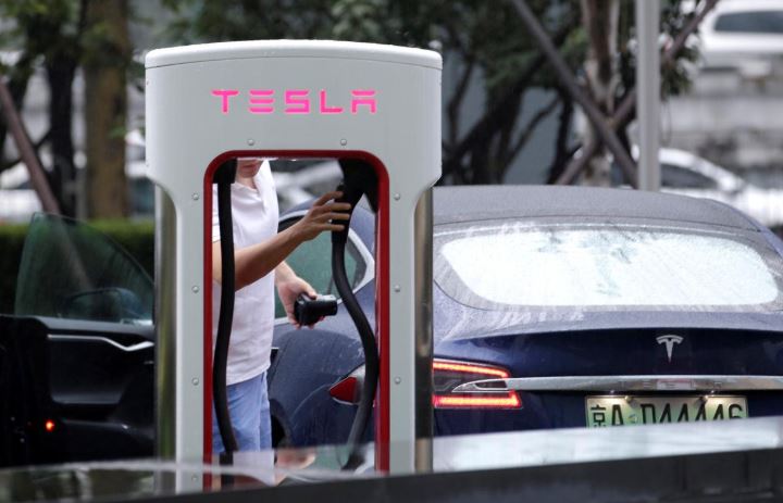 A man finishes charging his Tesla car at a charging point outside Tesla China headquarters in Beijing, China.