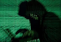 A man holds a laptop computer as cyber code is projected on him in this illustration picture taken on May 13, 2017. Capitalizing on spying tools believed to have been developed by the U.S. National Security Agency, hackers staged a cyber assault with a self-spreading malware that has infected tens of thousands of computers in nearly 100 countries.
