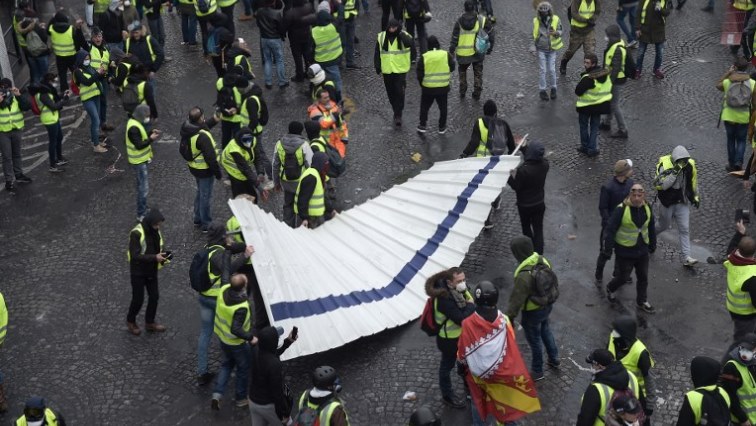 Demonstrators hold a metal barrier during a protest of Yellow vests (Gilets jaunes) against rising oil prices and living costs on the Champs Elysees, in Paris.