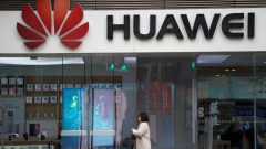 A woman walks by a Huawei logo at a shopping mall in Shanghai, China.