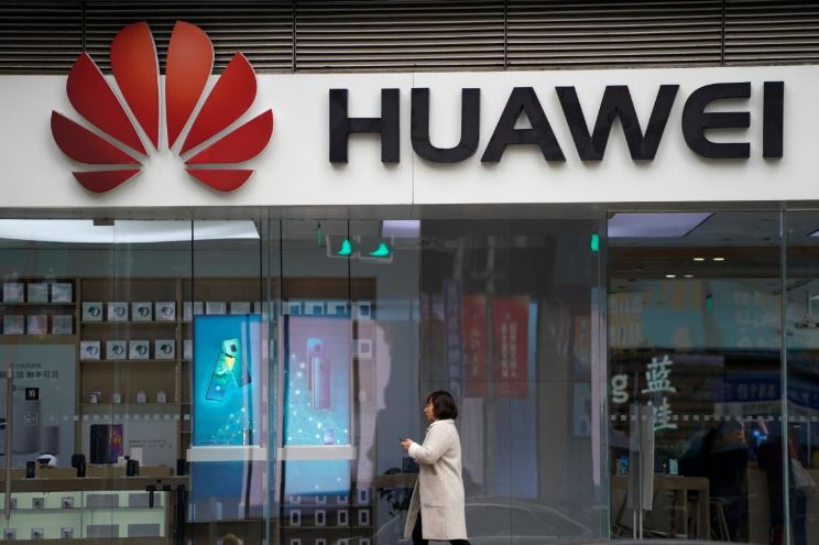 A woman walks by a Huawei logo at a shopping mall in Shanghai, China.