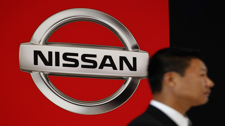 A man standing next to Nissan logo