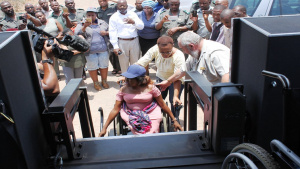 Woman on a wheelchair assisted to get on a game drive vehicle.