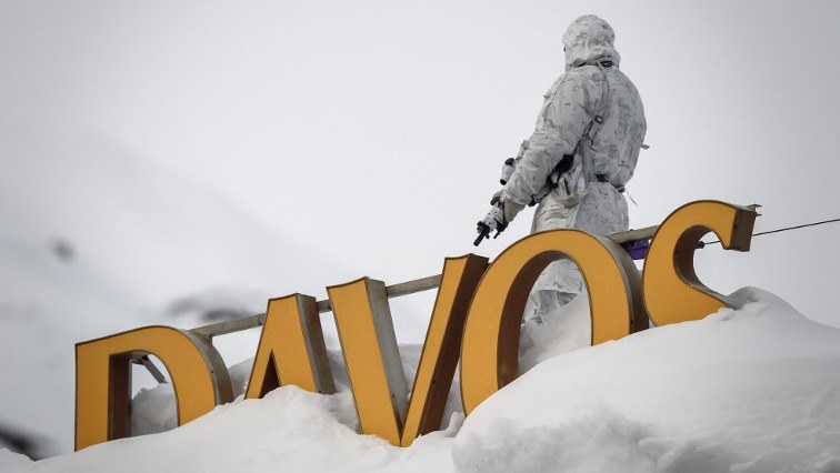 A policeman wearing camouflage clothing stands on the rooftop of a hotel, next to letters covered in snow reading 'Davos', near the Congress Centre ahead of the World Economic Forum (WEF) annual meeting.