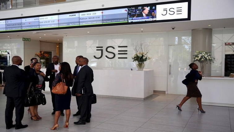 File: People chat in front of a reception with an electronic board displaying movements in major indices at the Johannesburg Stock Exchange building in Sandton Johannesburg, March 14, 2016.