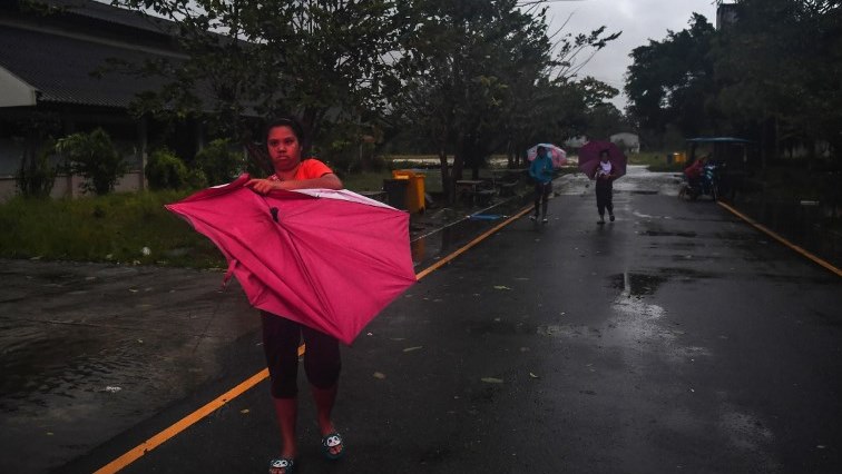 A young woman struggles with an umbrella outside an evacuation centre after being displaced by tropical storm Pabuk in the southern Thai province of Nakhon Si Thammarat on January 4, 2019.