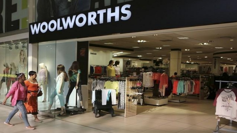 Shoppers walk into a Woolworths store at a shopping center in Lenasia, south of Johannesburg, file.