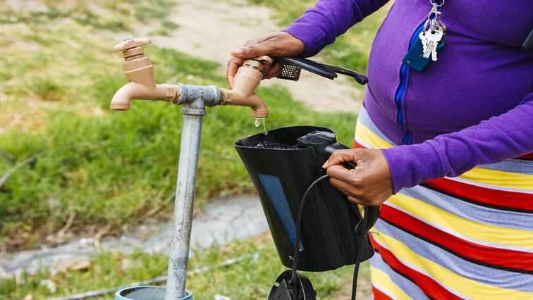 A resident fills a plastic kettle with water from a communal tap