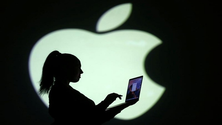 Silhouette of woman holding a laptop near the Apple logo