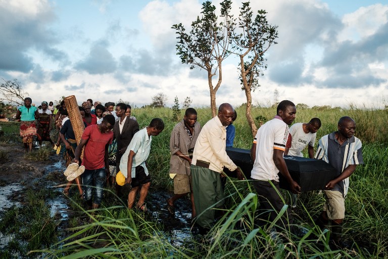 People carry the coffin of Tomas Joaquim Chimukme during his funeral, after his home collapsed following a strong cyclone that hit Beira, Mozambique, on March 20, 2019. - Five days after tropical cyclone Idai cut a swathe through Mozambique, Zimbabwe and Malawi, the confirmed death toll stood at more than 300 and hundreds of thousands of lives were at risk, officials said. (Photo by Yasuyoshi CHIBA / AFP)