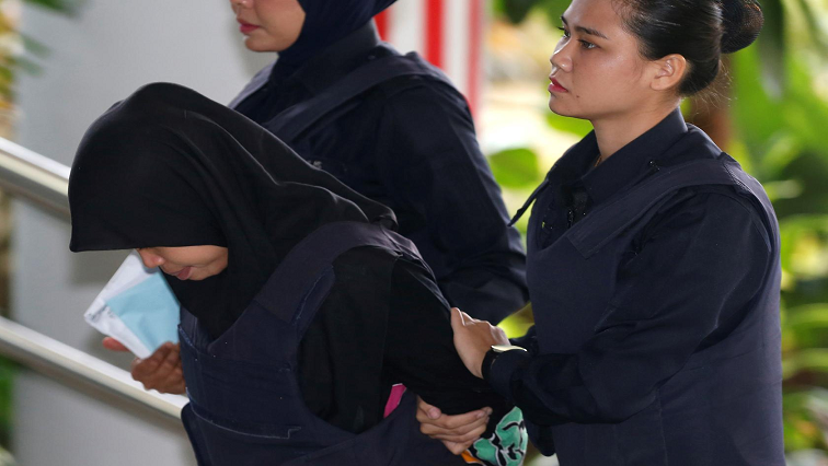 Siti Aisyah held in cuffs by female officer.