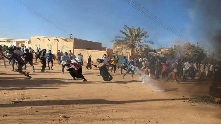Sudanese protesters running from teargas