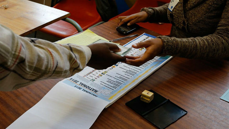 A voter receives ballot papers from election official in Johannesburg in 2014.