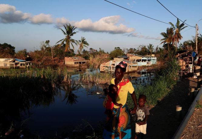 A woman walks with her children past flooded houses in the aftermath of Cyclone Idai in Tica near Beira.