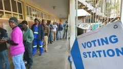 People standing in a line outside voting station