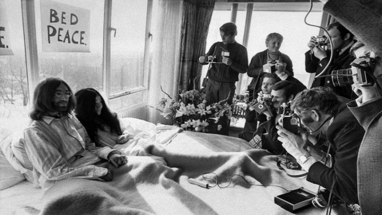 John Lennon and Yoko Uno in bed surrounded by journalists