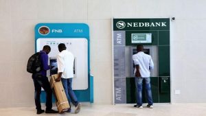 People standing by FNB and Nedbank ATMs