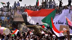 A military officer is carried by the crowd as demonstrators chant slogans and carry their national flags, after Sudan's Defense Minister said that President Omar al-Bashir had been detained 'in a safe place'.
