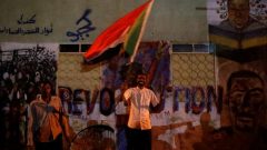 A Sudanese protester waves a national flag as he arrives a mass protest in front of the Defence Ministry in Khartoum, Sudan.