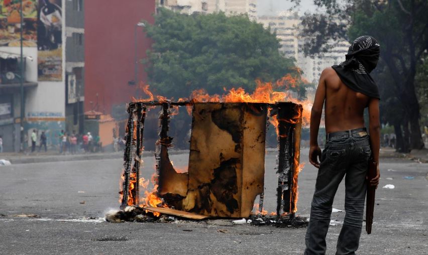 A demonstrator stands next to a burning barricade during a protest against the government of Venezuelan President Nicolas Maduro in Caracas.